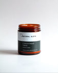 An amber glass jar Beeswax candle with a white and dark green label reading 'Natural Sloth Christmas Tree' on a clean white background.