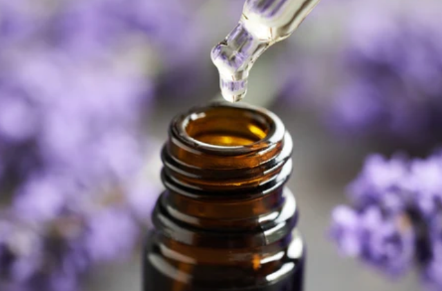 Brown glass bottle with dropper over a blurred background of purple flowers